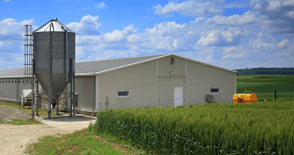 Farm building with silo and green field.